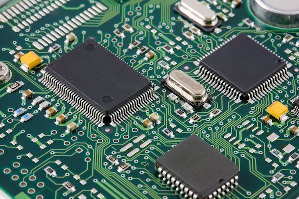 Close-up view of a green printed circuit board with multiple microchips, electronic components, and connecting tracks.