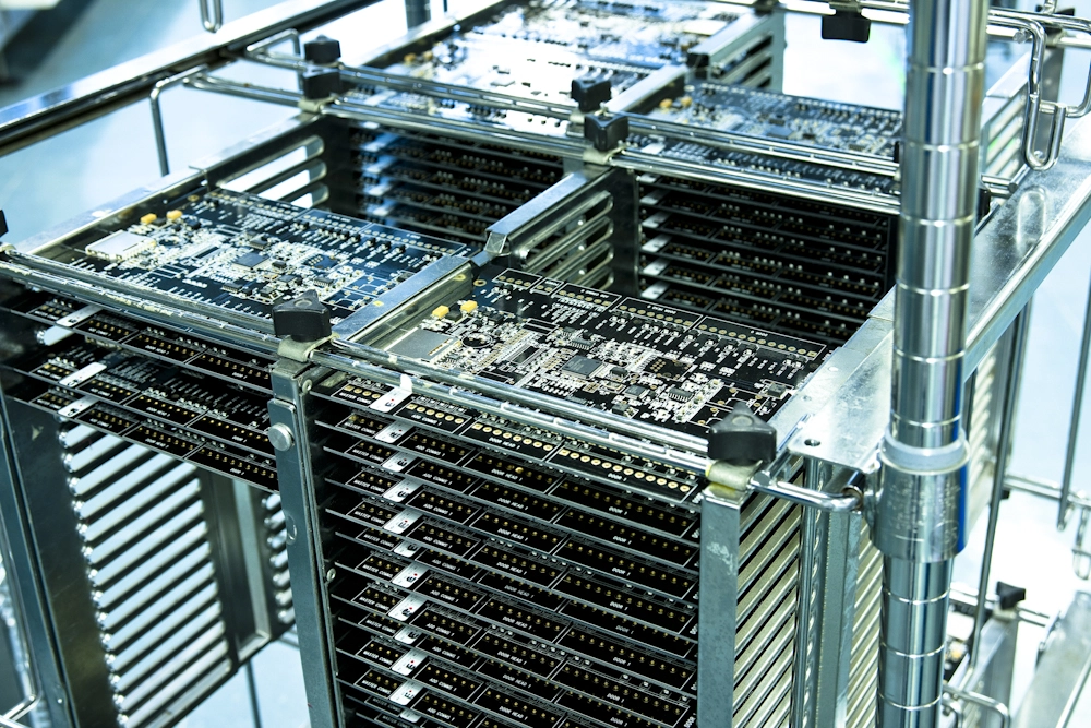 Stacks of computer circuit boards arranged in metal racks, likely in an electronics manufacturer or assembly facility.