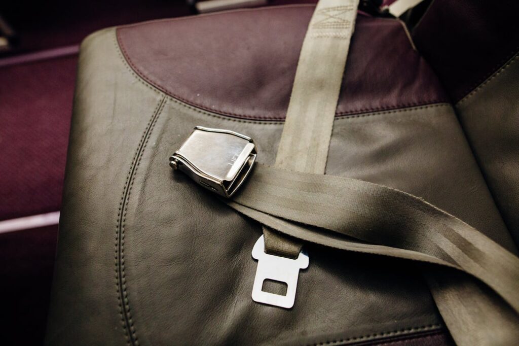 A close-up of an aeroplane seatbelt lying across a dark leather and fabric seat, capturing the precision found in aerospace electronics manufacturing.