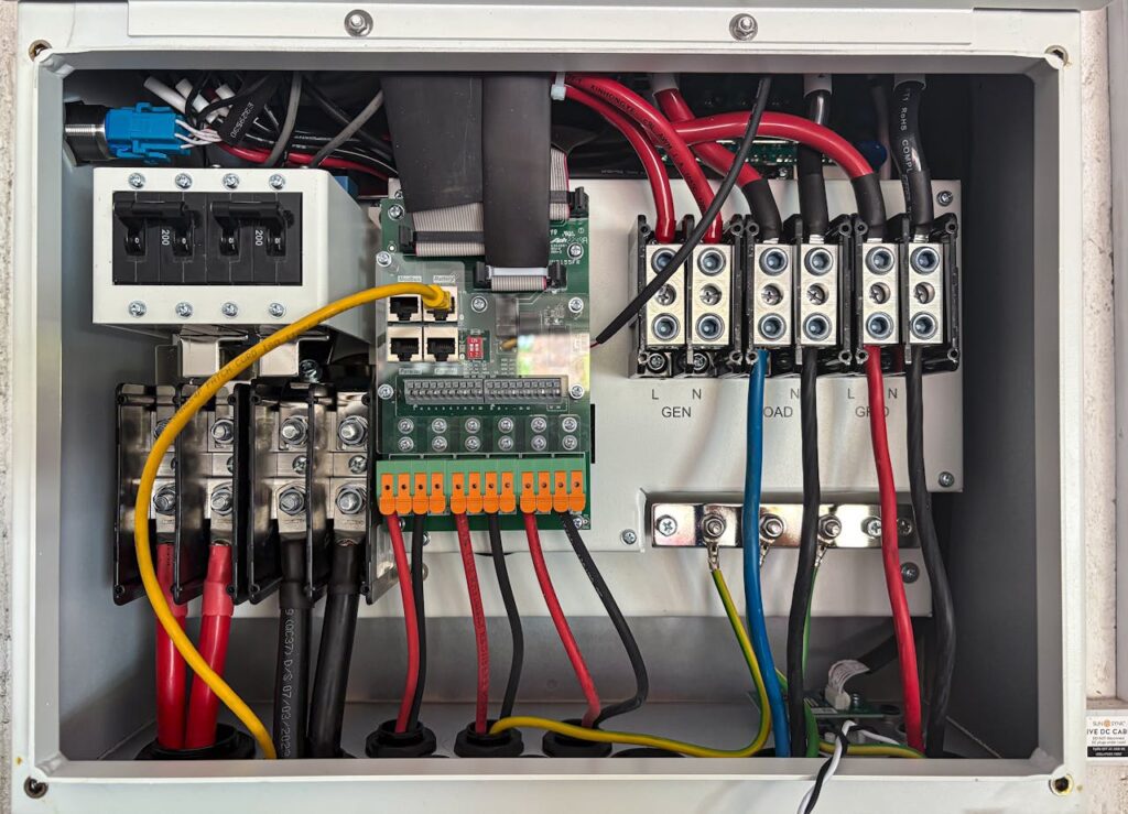 Electrical control panel with circuit breakers, wiring, terminal blocks, and a green circuit board—ideal for data centre electronics manufacturing—displaying organised red, black, yellow, green, and blue cables.