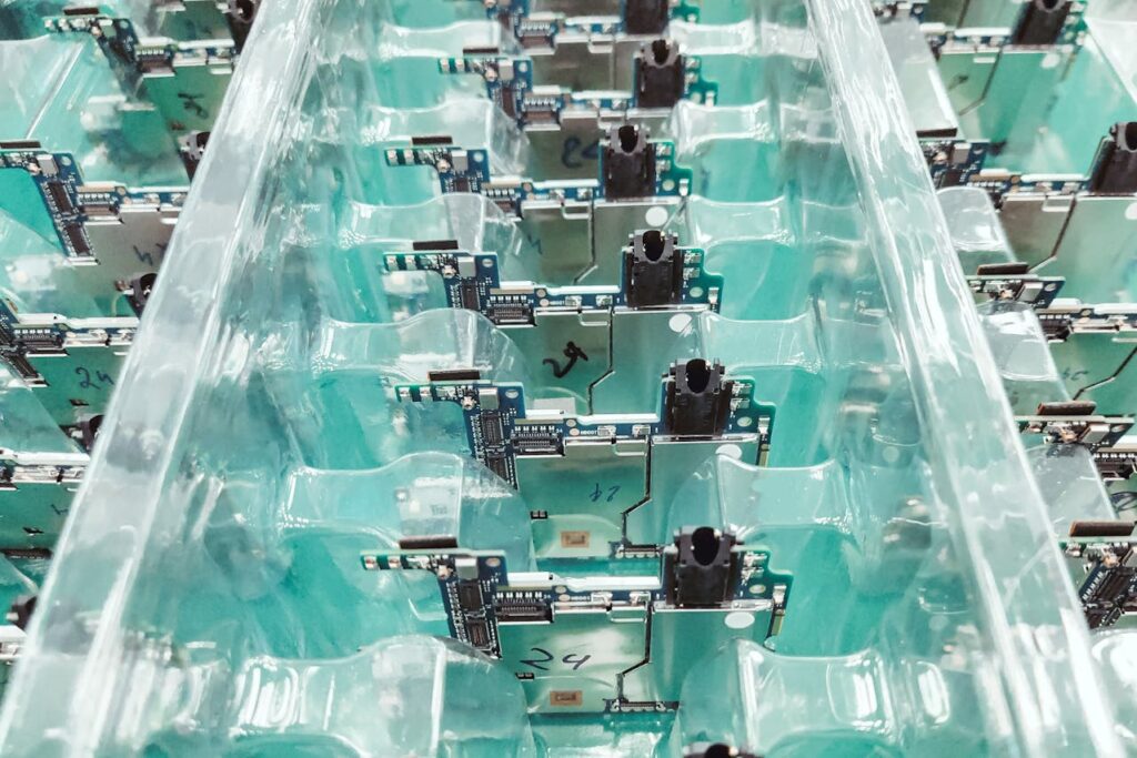 Close-up view of several electronic circuit boards arranged in clear plastic trays, each board secured in its own compartment—ideal for precision and reliability in defence electronics manufacturing.