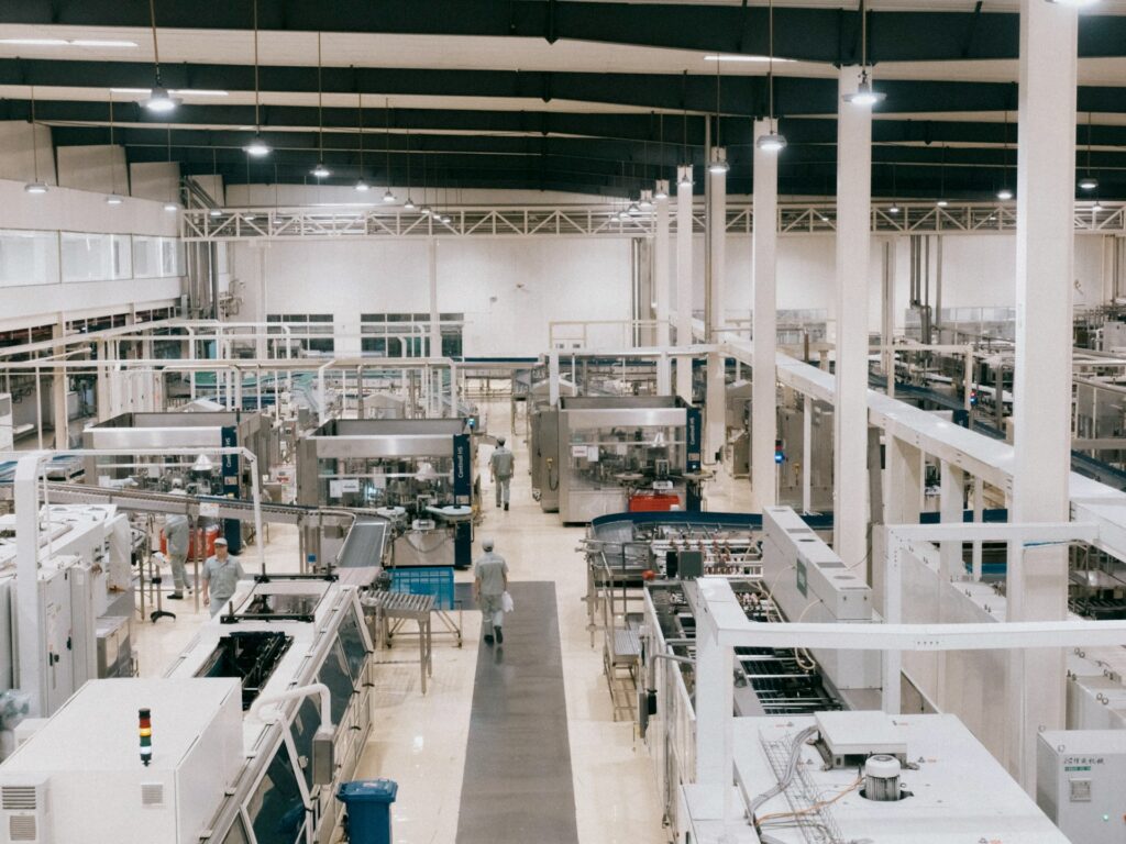 Wide view of a spacious, brightly lit factory floor dedicated to industrial electronics manufacturing, with rows of machinery and a single person walking down the central aisle.